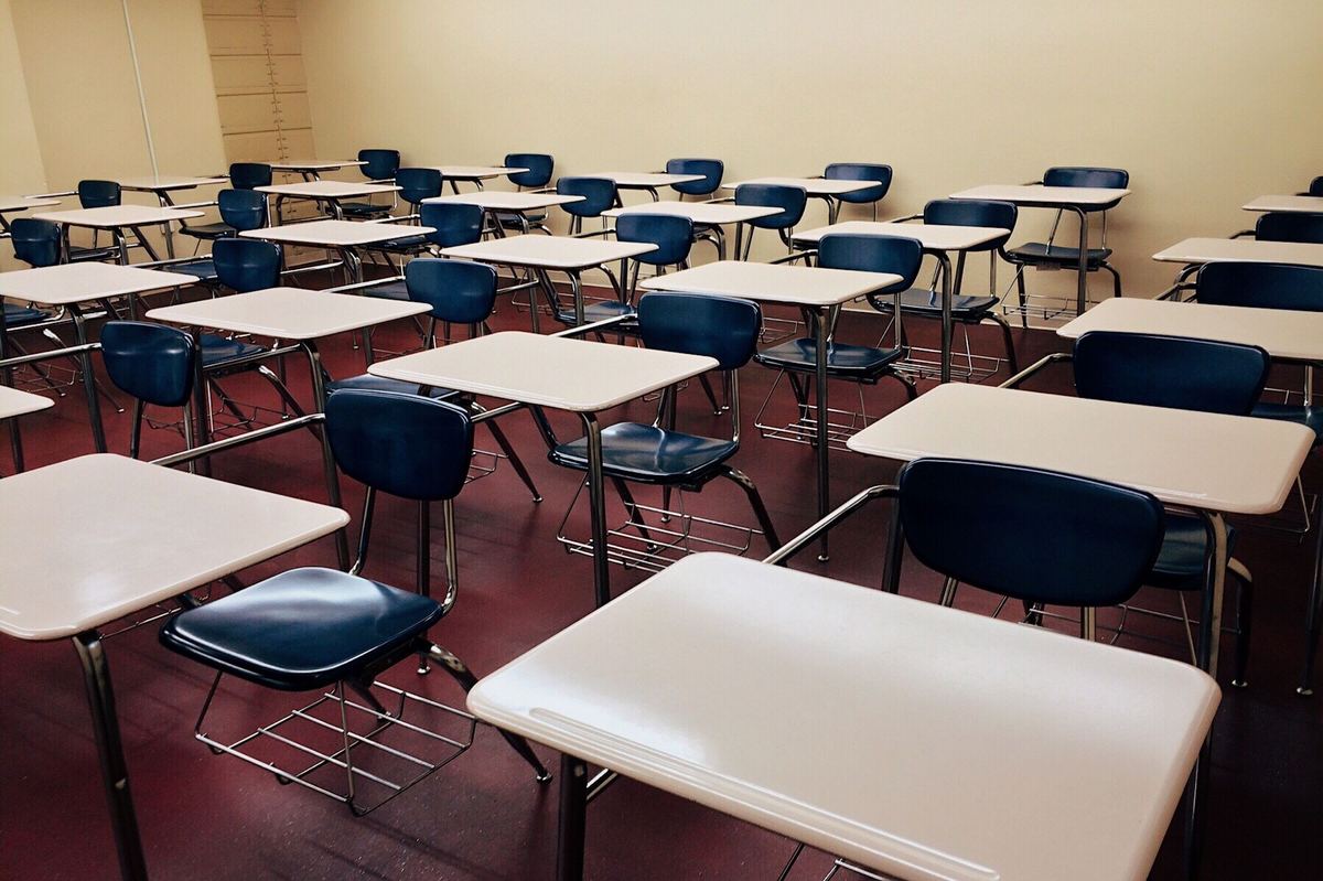 Aula buida amb files de pupitres, preparada per a una prova escrita